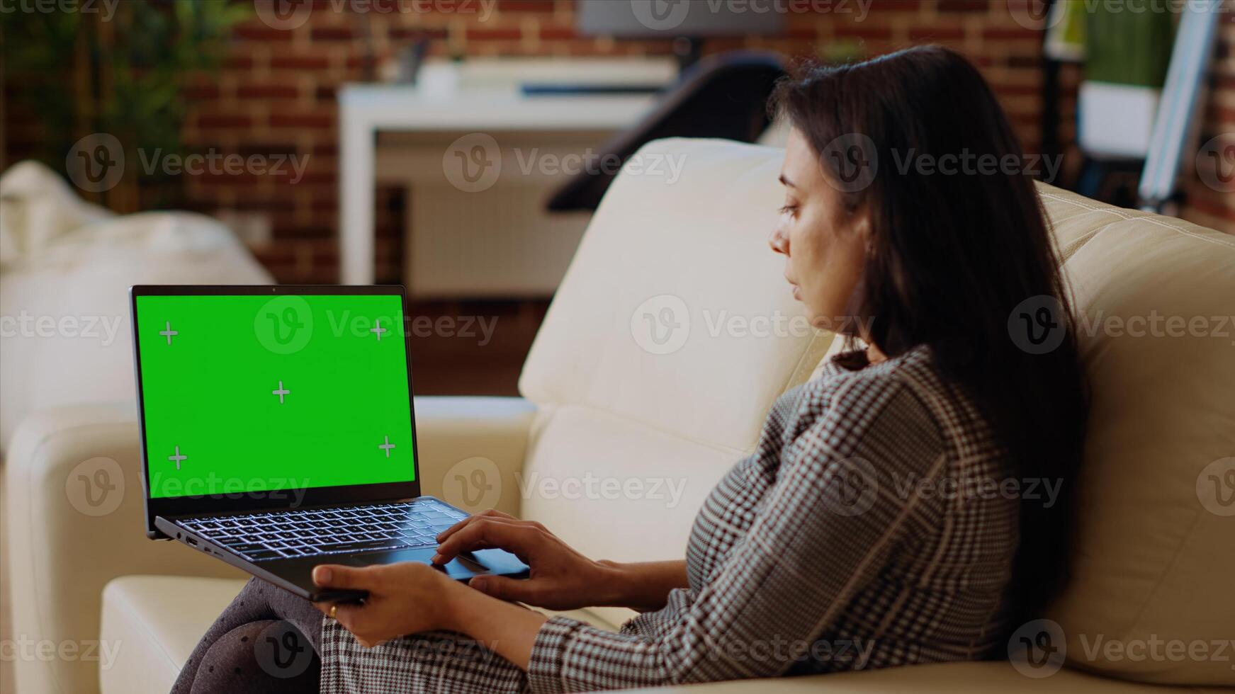 Person checking emails on isolated screen laptop during work from home. Indian woman in cozy bright apartment doing job tasks, reading business messages on chroma key notebook photo