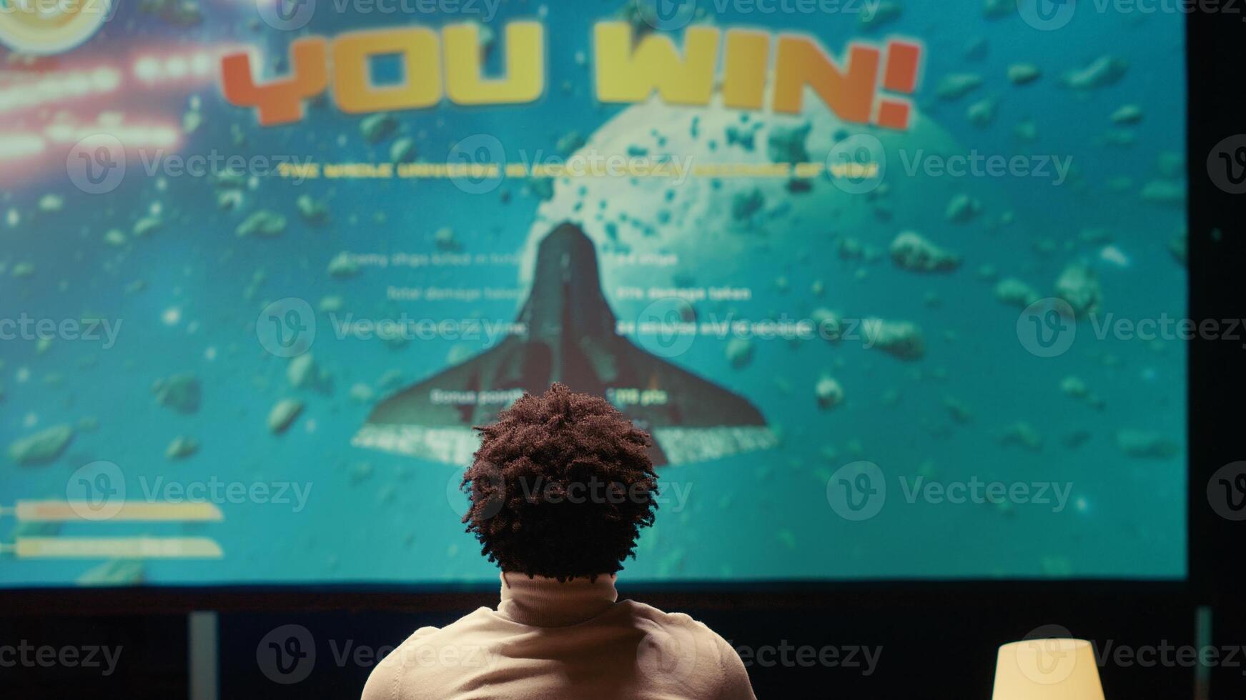 BIPOC man happy after winning SF game and destroying enemy spacecrafts. Close up shot of player feeling excited after victory in videogame displayed on widescreen TV, defeating boss to save galaxy photo