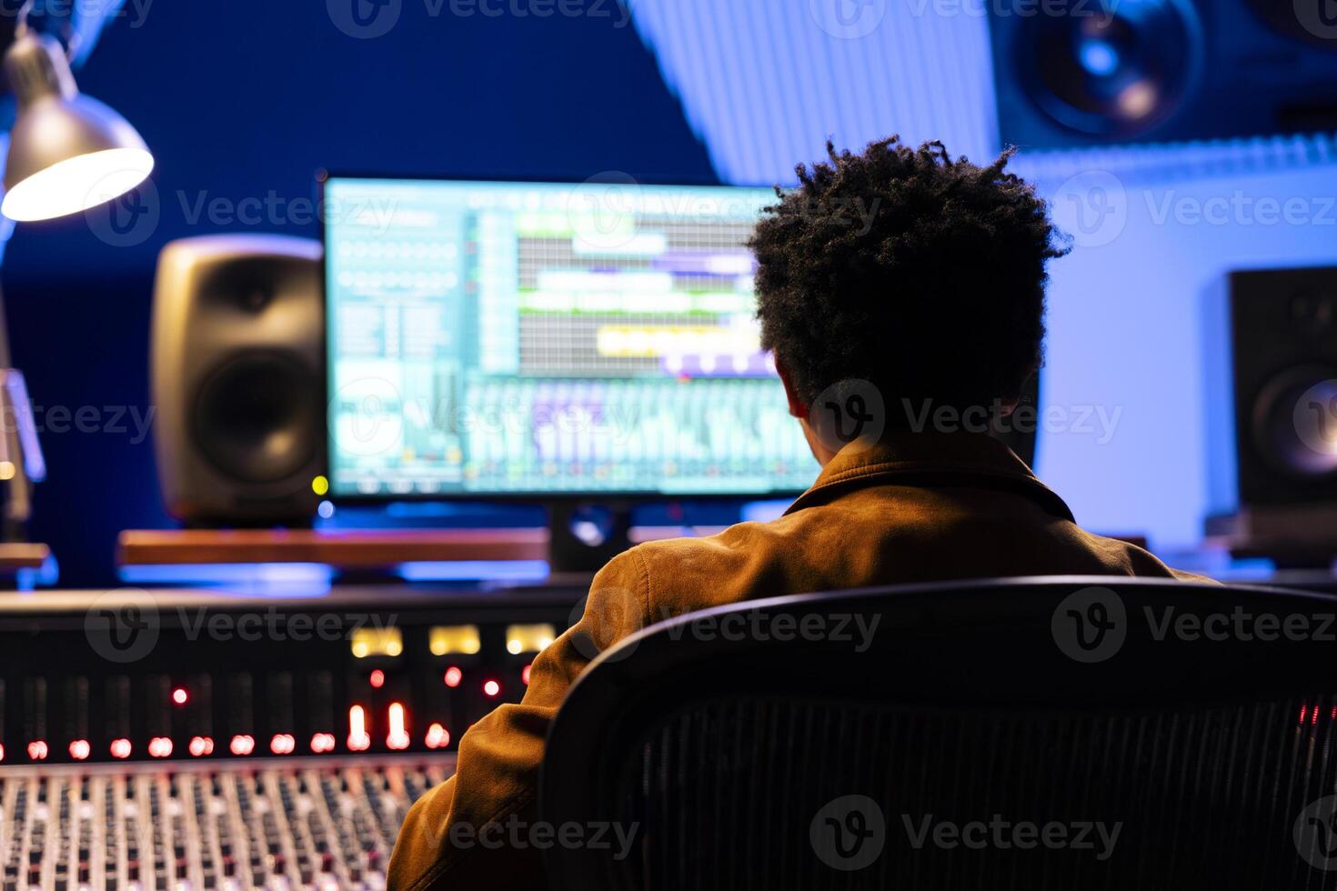 African american record composer mixing and mastering songs with audio software, working with auto sliders and buttons to adjust sound volume levels. Sound engineer creating new music. photo