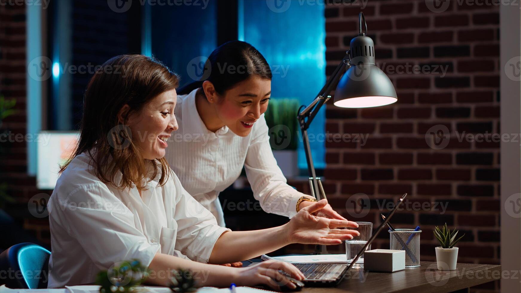 Cheerful coworkers read email on laptop received from customer, excited after managing to secure lucrative deal for company. Colleagues celebrate finalizing agreement with business partners, camera B photo
