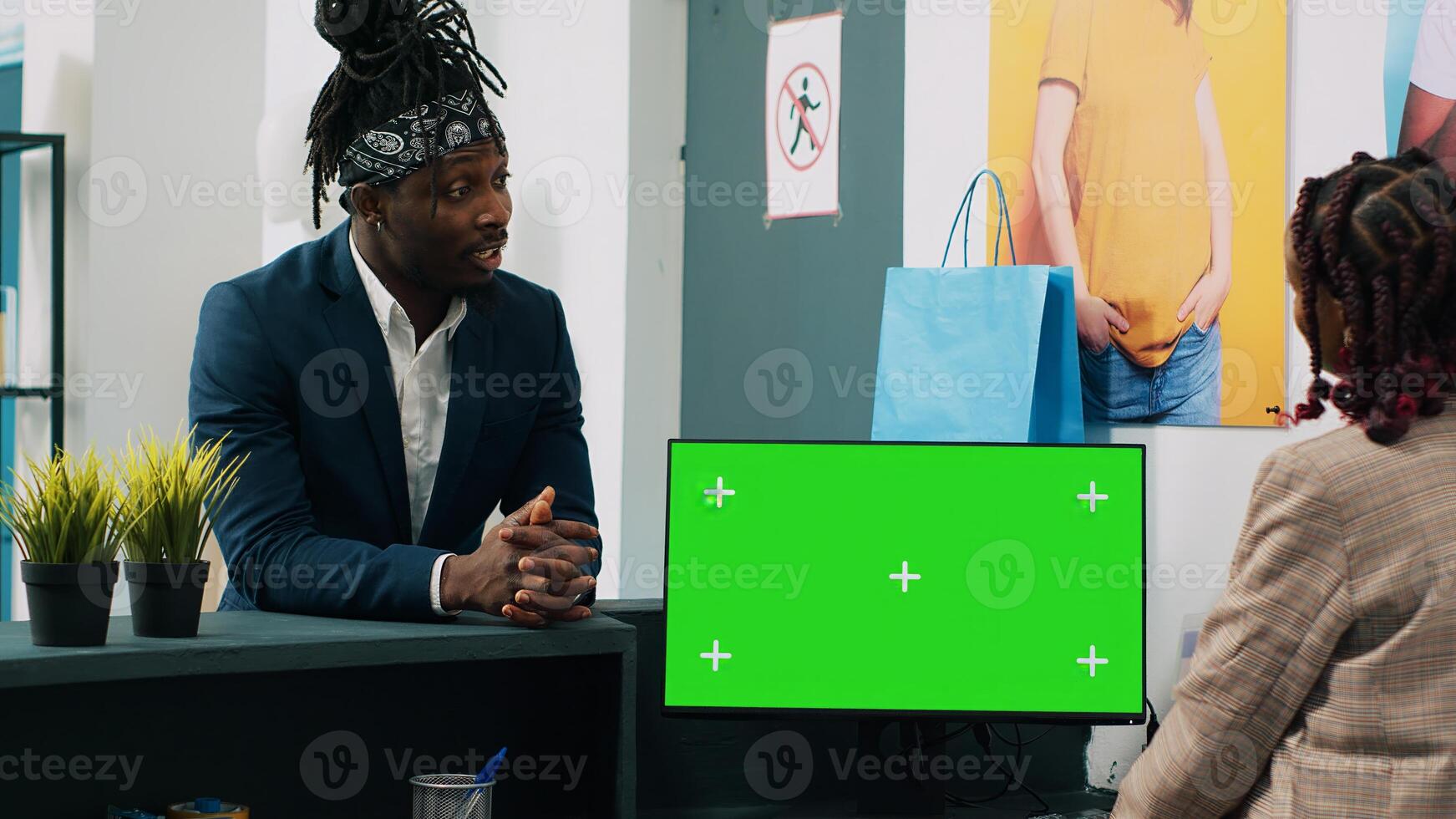 African american employee works with greenscreen on pc at cash register, preparing clothes order to client at checkout. Retail worker using computer with isolated chromakey display. Camera A. photo
