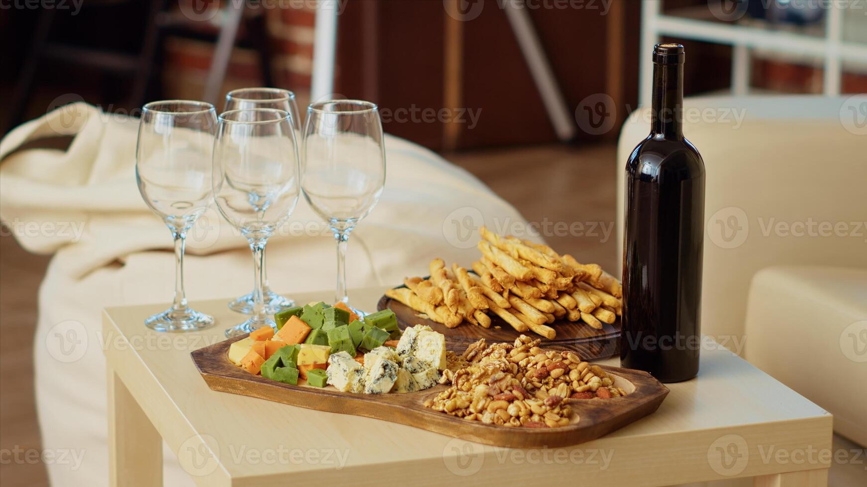 Close up shot of charcuterie board and gourmet cheese platter set up by hosts to properly welcome guests arriving soon at apartment party. Wine bottle and glasses next to appetizers in living room photo