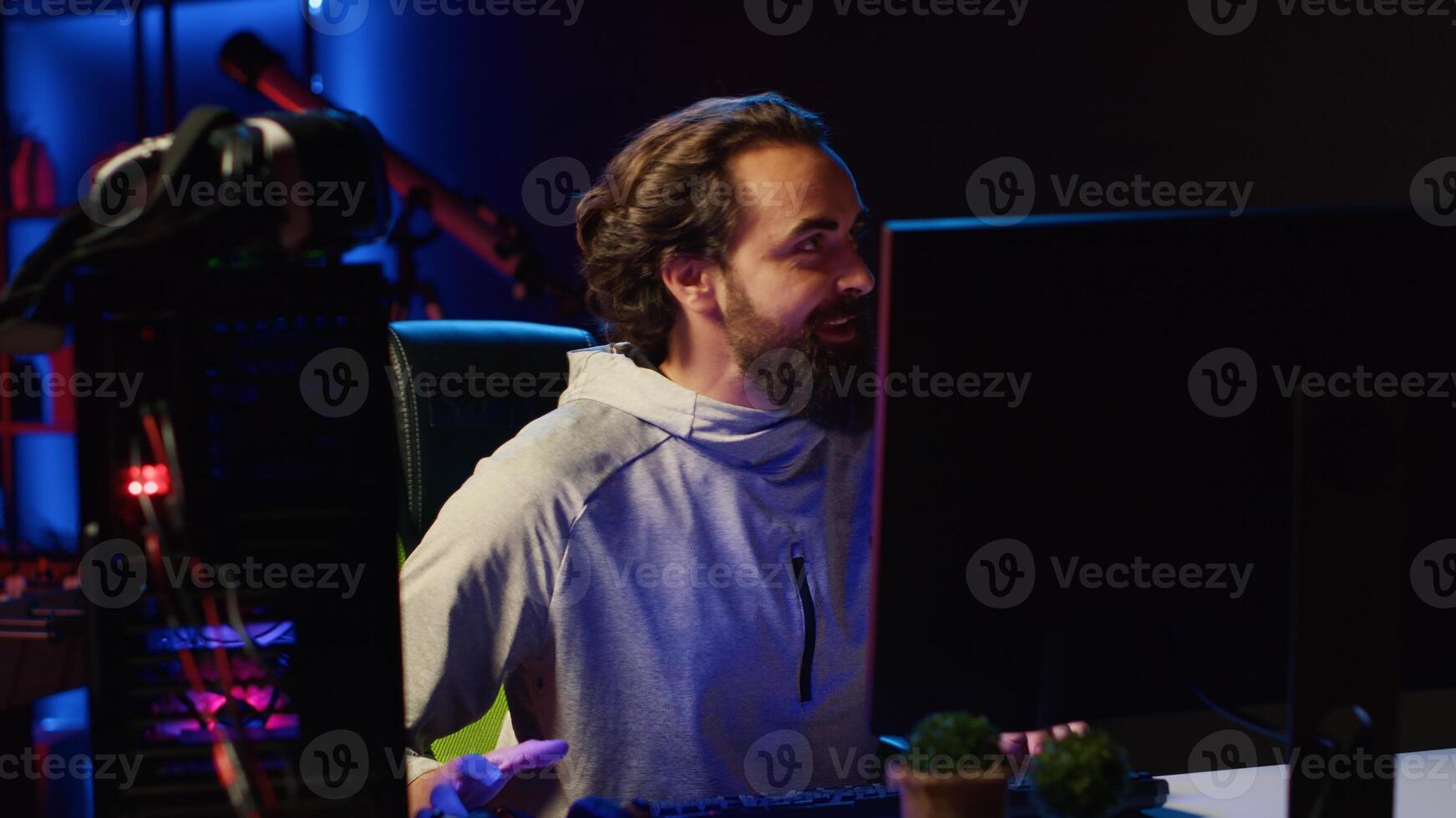 Streamer arriving in studio, ready to start streaming for online viewers, talking with them. Pro gamer broadcasting from dark living room, greeting fans watching him on internet channel photo