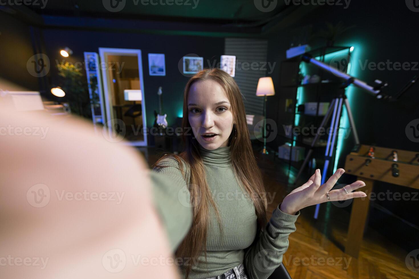 POV of social media star using cellphone camera to capture welcoming intro for vlogging channel. Girl in home studio connecting with loyal audience during livestream, filming with selfie stick photo