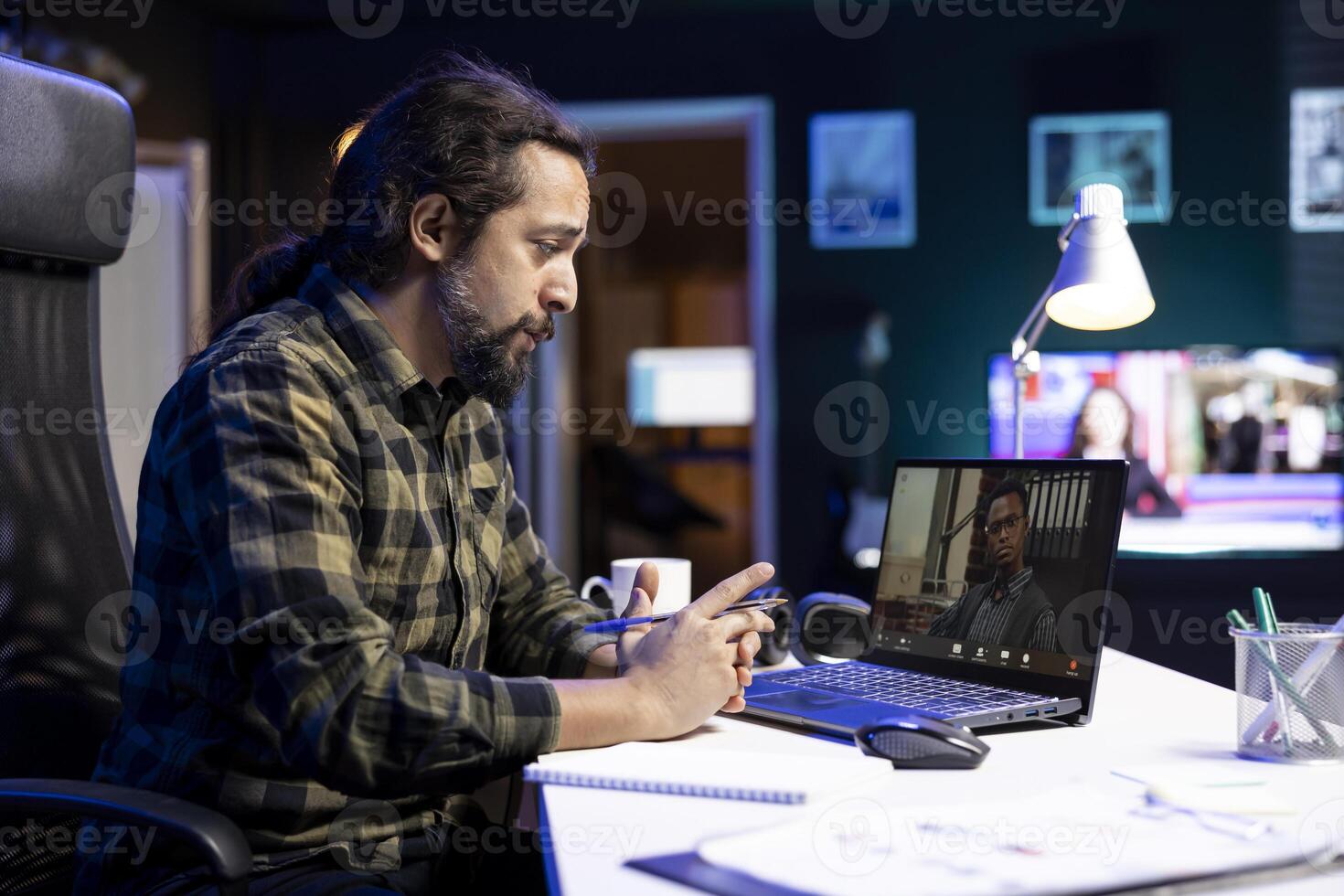 Two multiracial men engaged in a virtual meeting through the laptop. Young bearded man speaking with an individul on a call, having an online discussion. photo