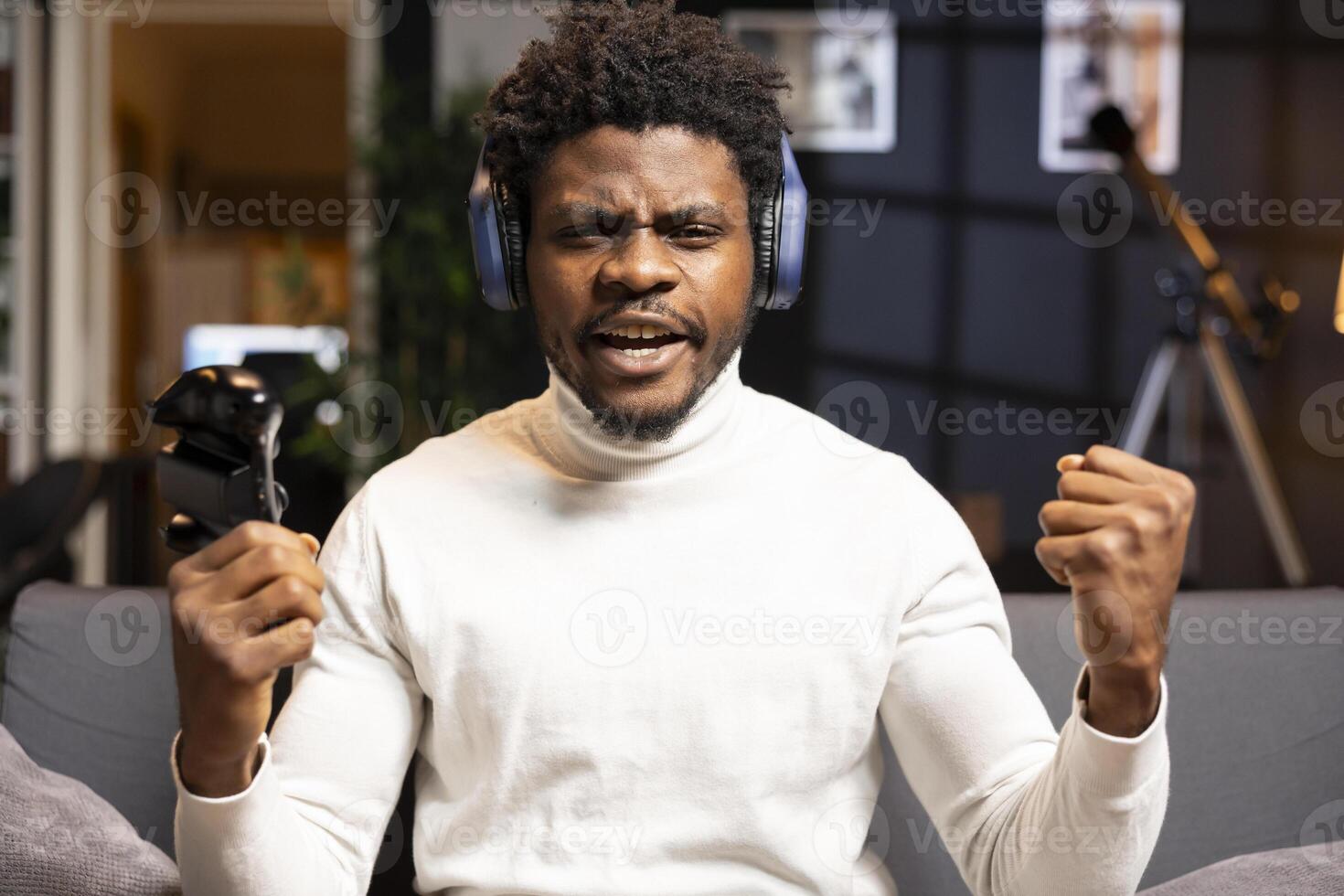Cheerful gamer bragging after finally defeating all enemies while playing on gaming console. Joyful african american man congratulating himself after winning videogame using controller photo
