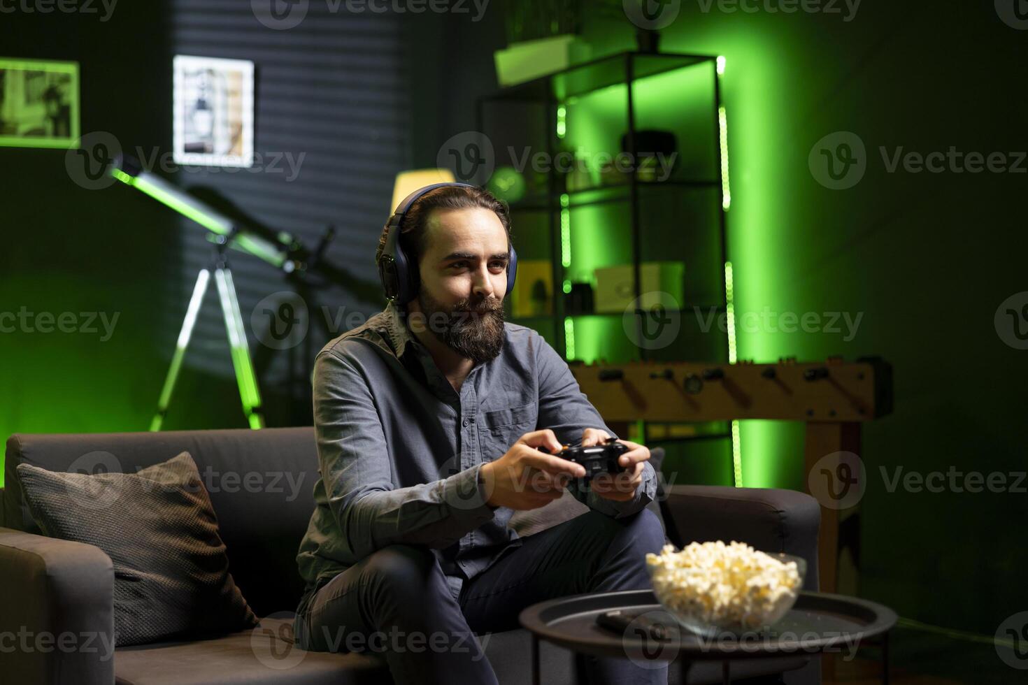 Smiling man focused on defeating enemies while playing videogames on gaming console with teammates, talking through headphones. Happy gamer fights rival players and chats with friends through headset photo