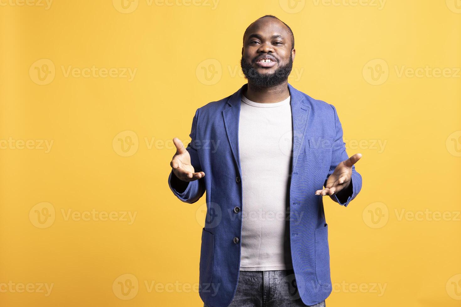 Portrait of smiling african american man posing with hands spread, exuding self assurance, isolated over studio background. Expressive BIPOC person moving arms while talking photo