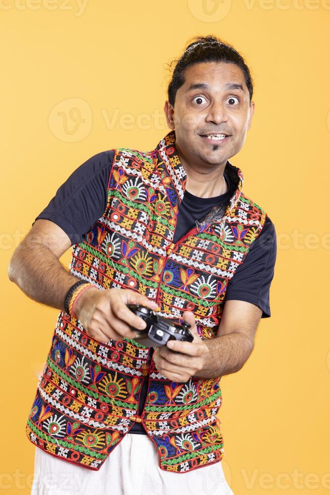 Portrait of joyous man being entertained by videogames, using controller, studio background. Jolly gamer having fun by participating in online multiplayer game using console system photo