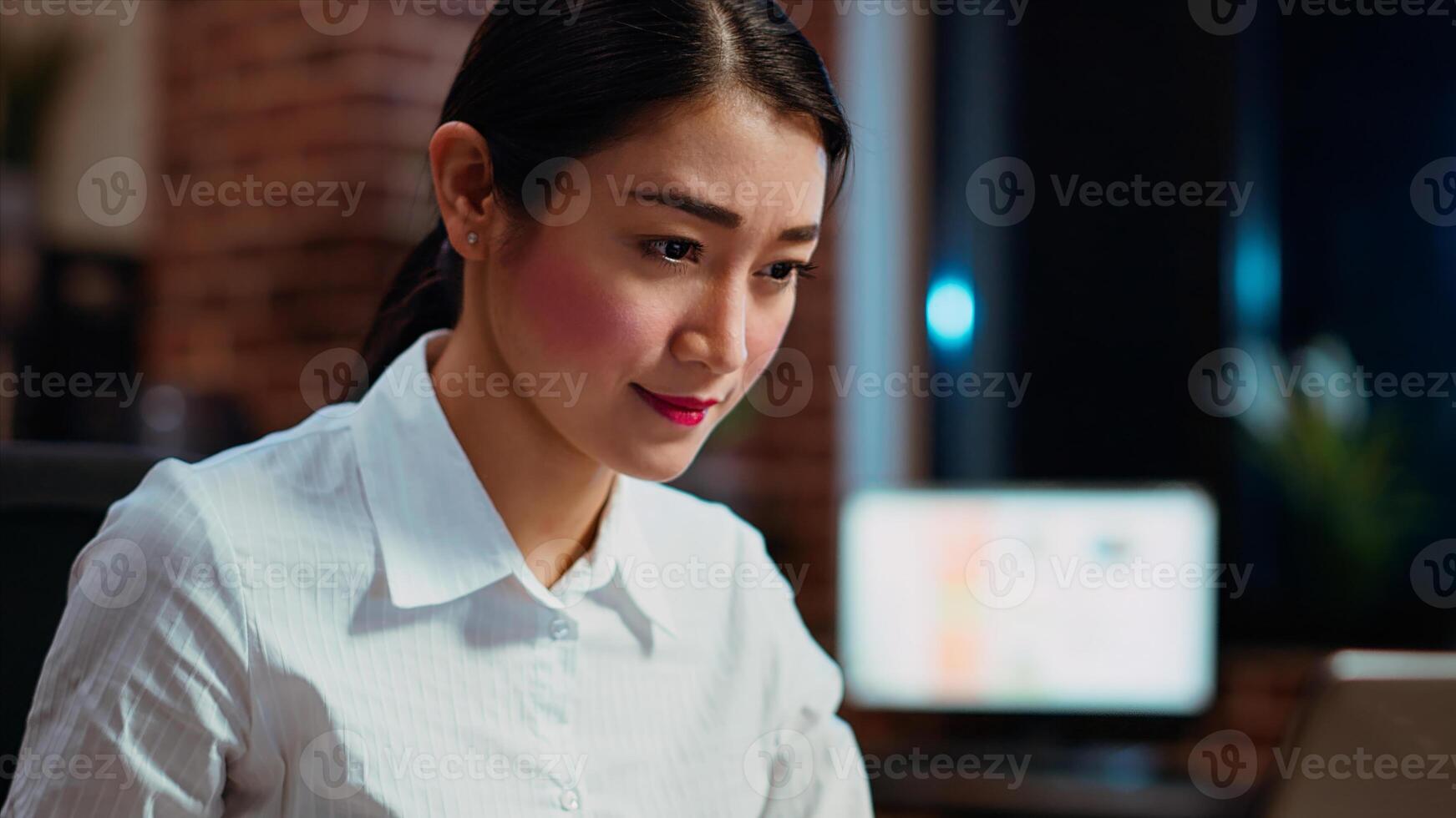 Close up shot of asian businesswoman researching key data for company project, doing tasks overnight. Office clerk looking over accounting figures on laptop screen late at night, typing on keyboard photo