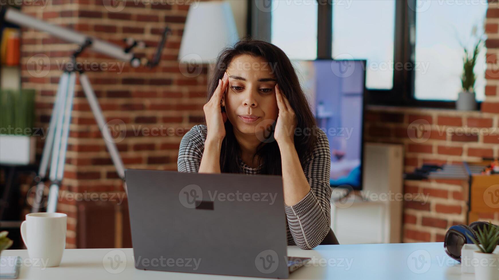 Self employed woman feeling ill, struggling to concentrate while working from home, hurting from headache. Exhausted freelancer suffering from sickness and stress while working on laptop, camera B photo