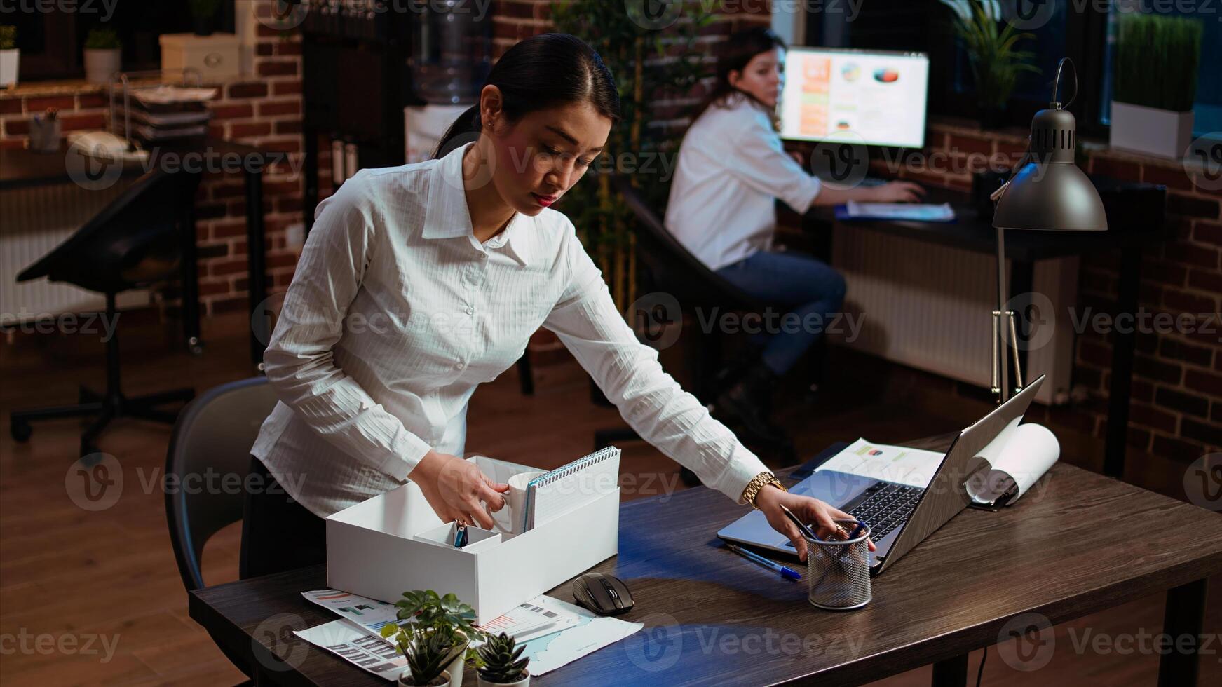 Frustrated employee packing desk things after being fired, saying goodbye to colleague. Upset employee feeling hurt, preparing to leave workplace after being discharged by management, camera A photo
