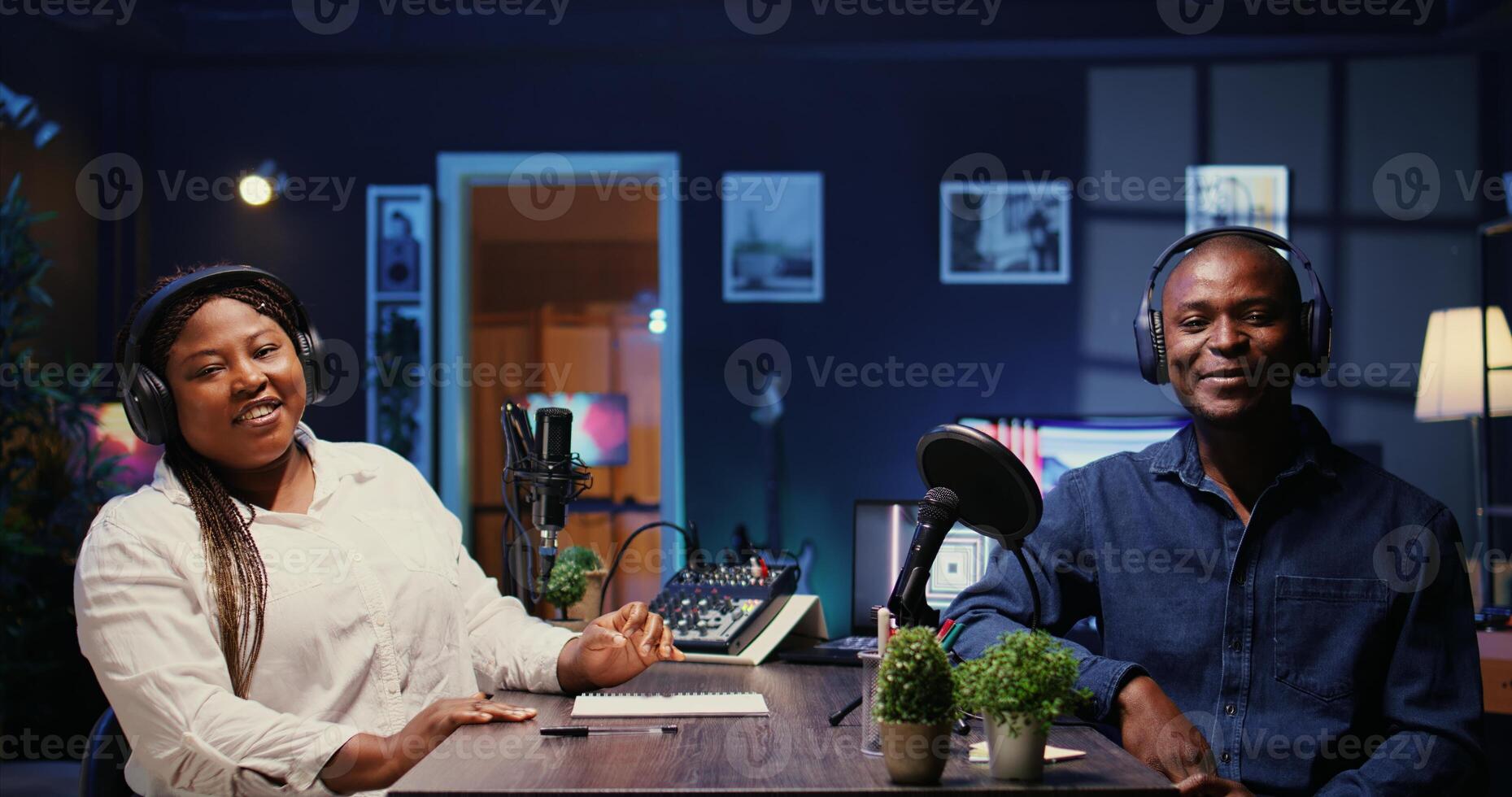 Man laughing during comedy focused podcast, entertained by funny presenter. African american guest amused by talking show host telling jokes to her and audience watching at home photo