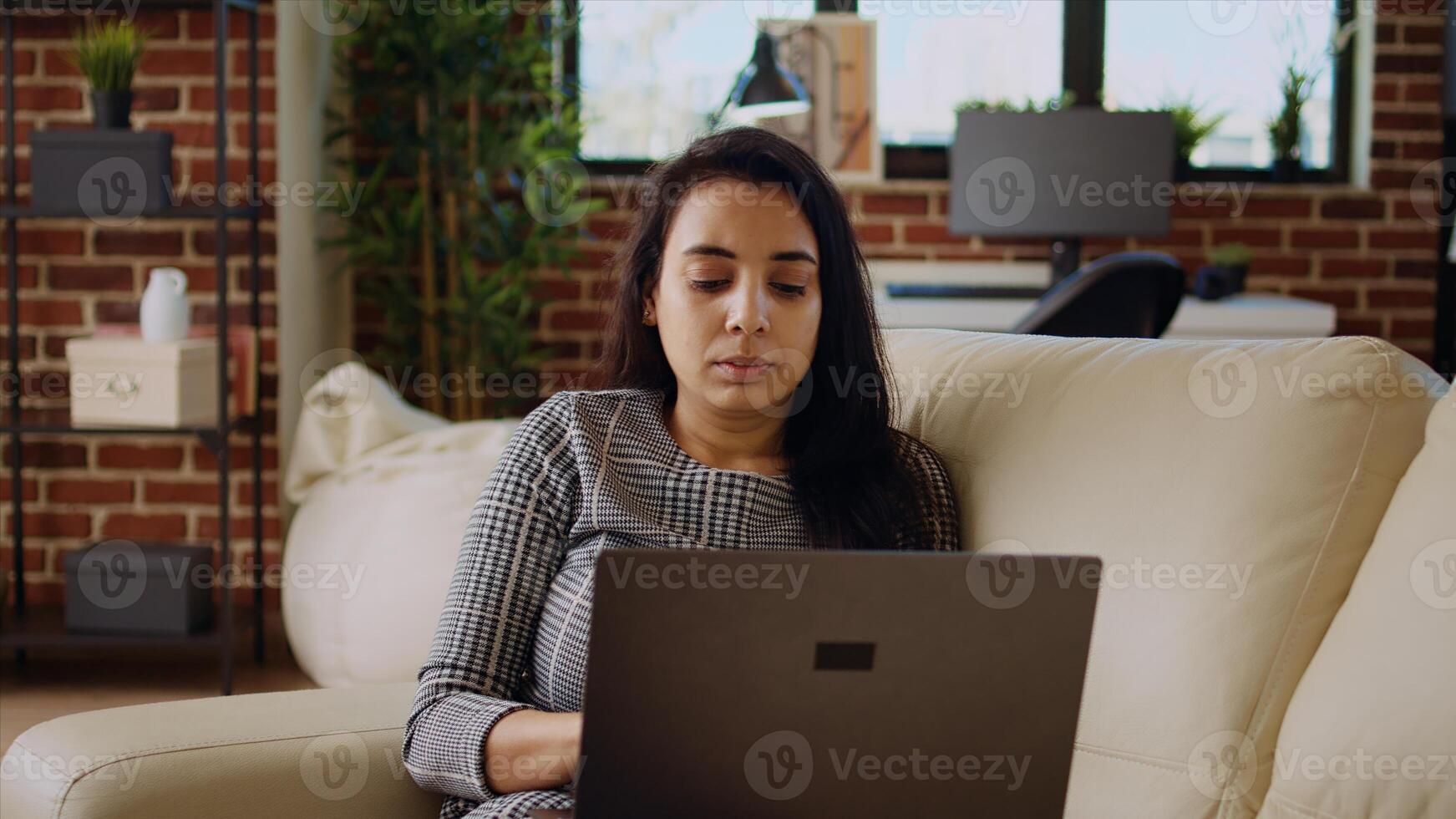 Teleworker lying on couch, remotely performing tasks in personal office. Relaxed freelancer inputting data on laptop while working from home, camera A dolly in close up shot photo