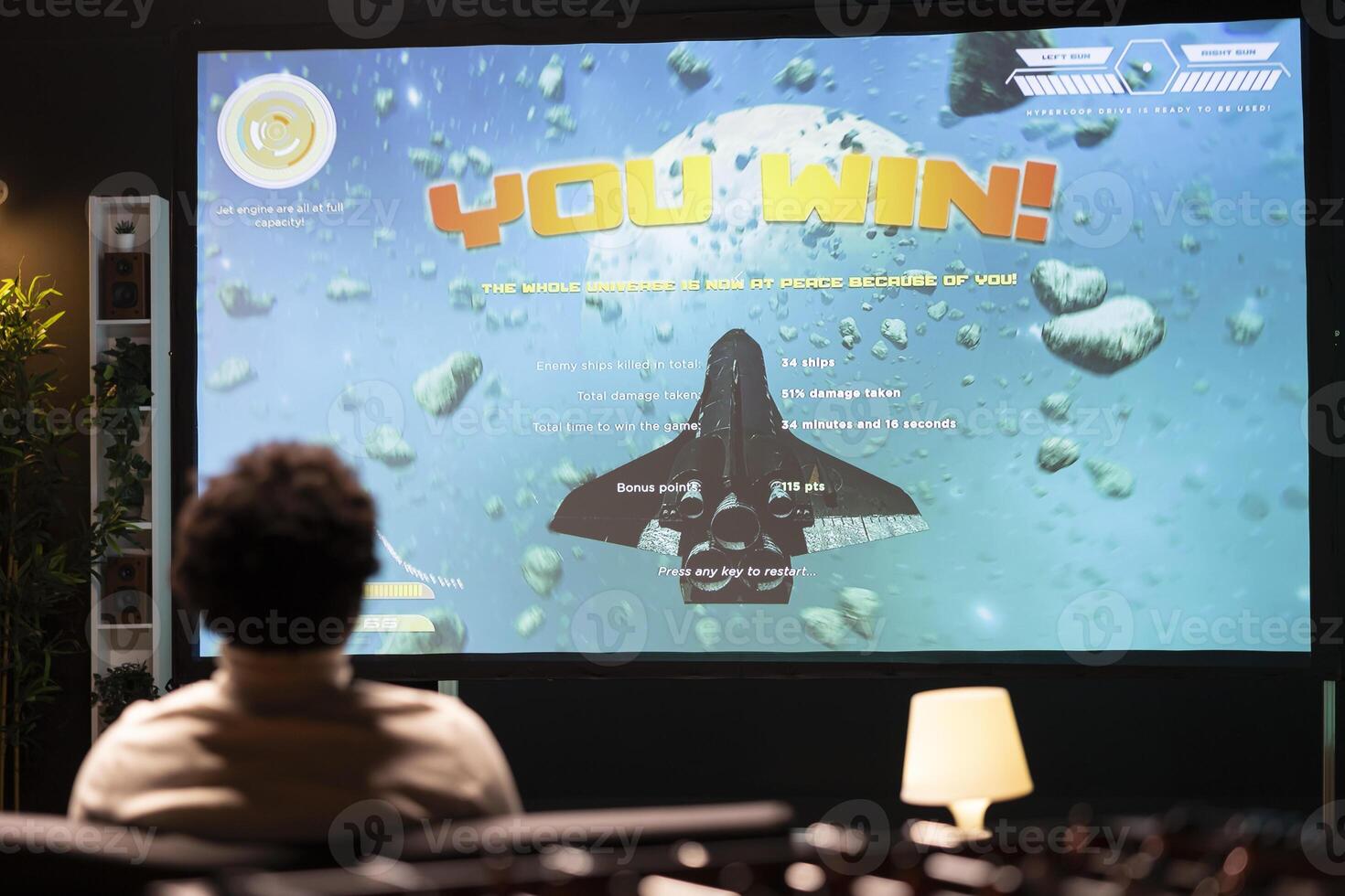 BIPOC man looking at winning screen of SF game on ultrawide smart TV. Player receiving victory message after completing all videogame levels, watching statistics roll on display photo