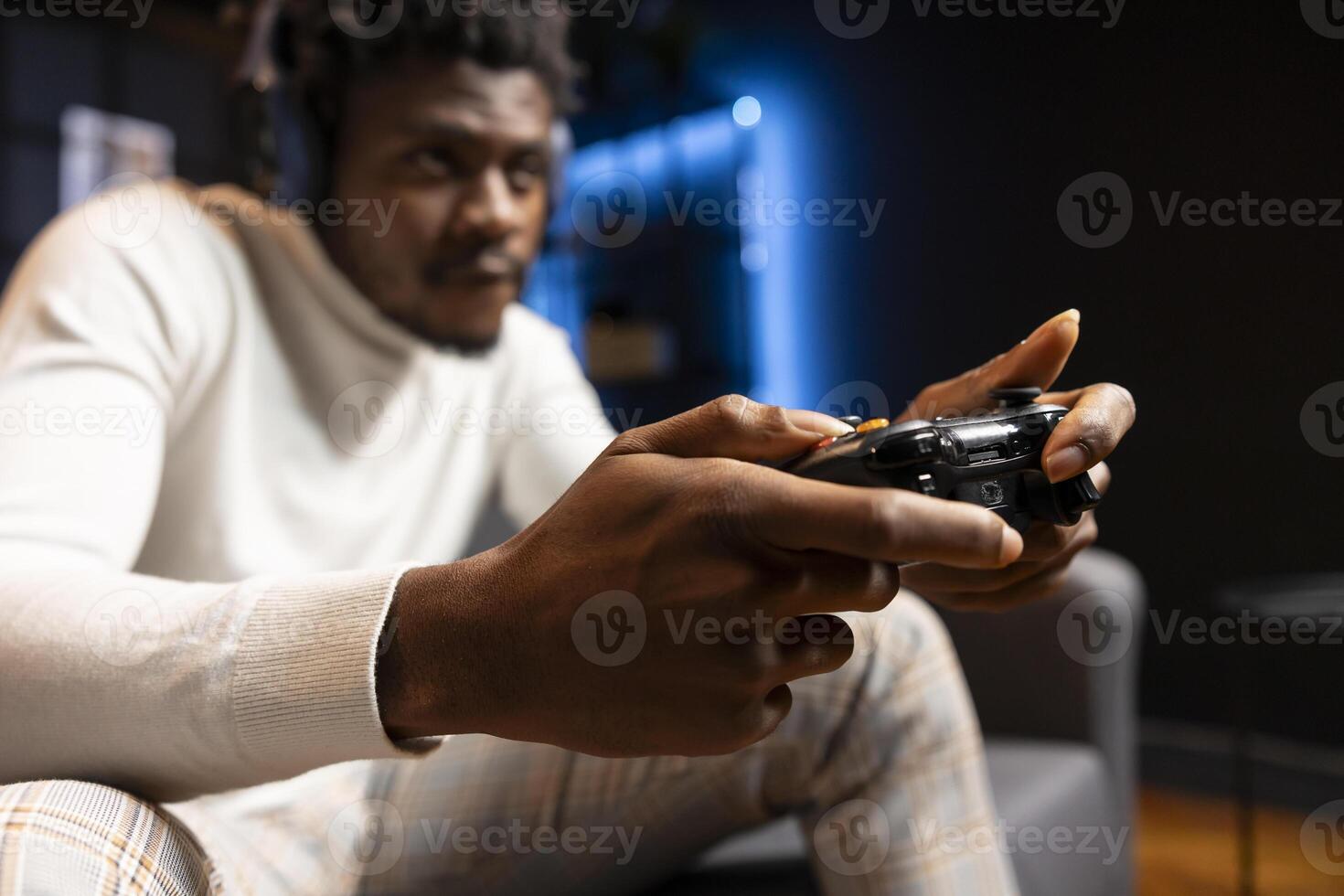 Man playing videogames using controller, having fun in blue neon illuminated room. Gamer competing in online multiplayer game on gaming console using gamepad, talk with friends through headset photo