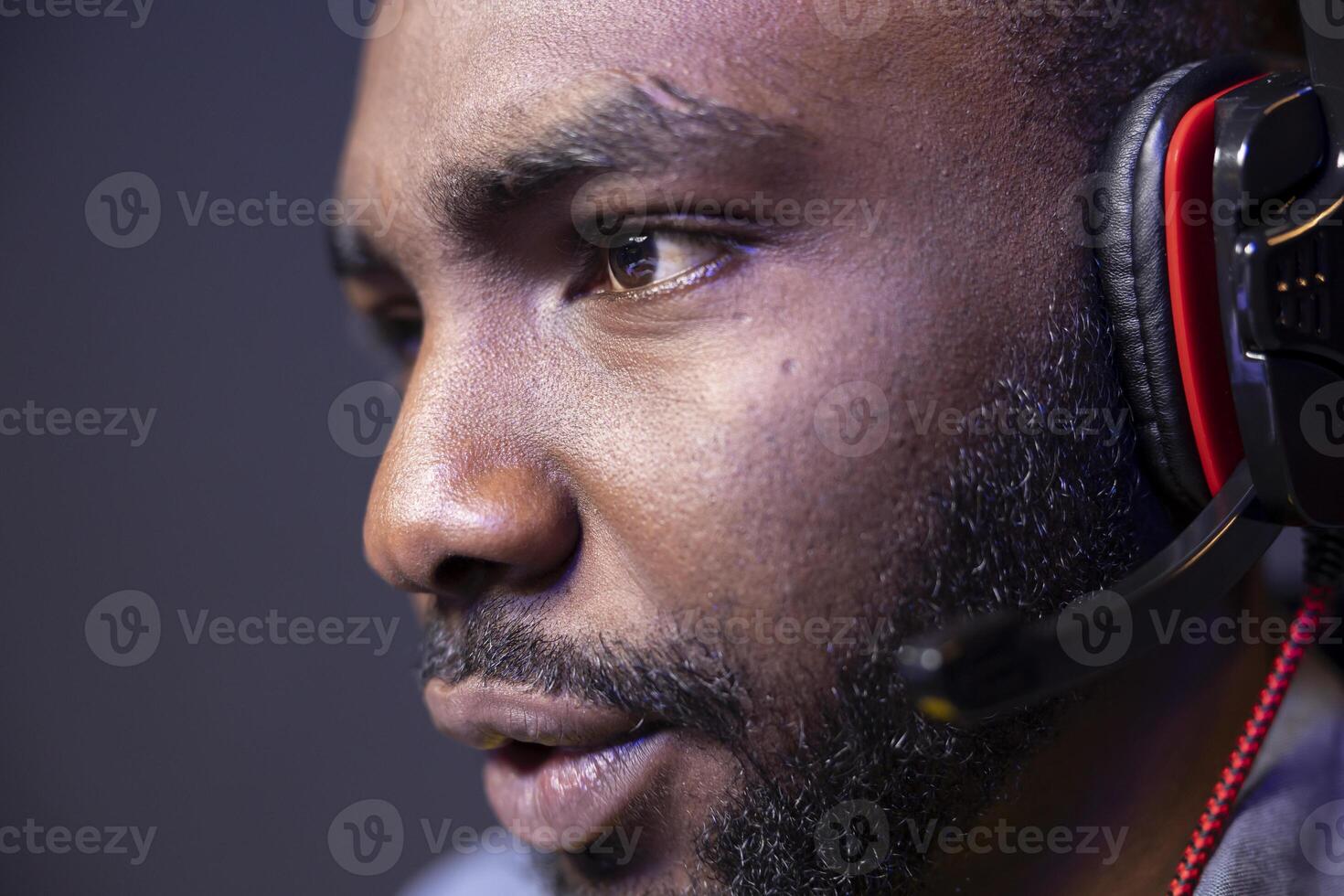 Close up of focused man playing videogame on powerful computer during online gaming championship, talking into headset. African american gamer taking part in Esports team, competing in game photo