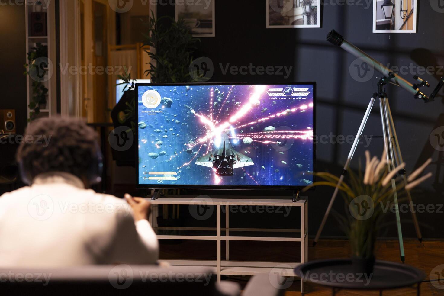 African american man in home theatre using cloud gaming service to play demanding science fiction videogame on TV. Gamer enjoying high quality graphics, streaming game over the internet photo