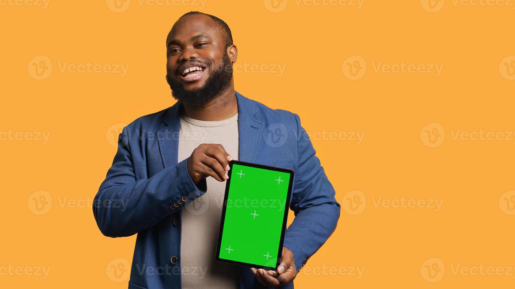 Amused african american man laughing while presenting tablet with green screen display, studio background. Joyous BIPOC person has fun during promotion for blank copy space mockup device, camera A photo