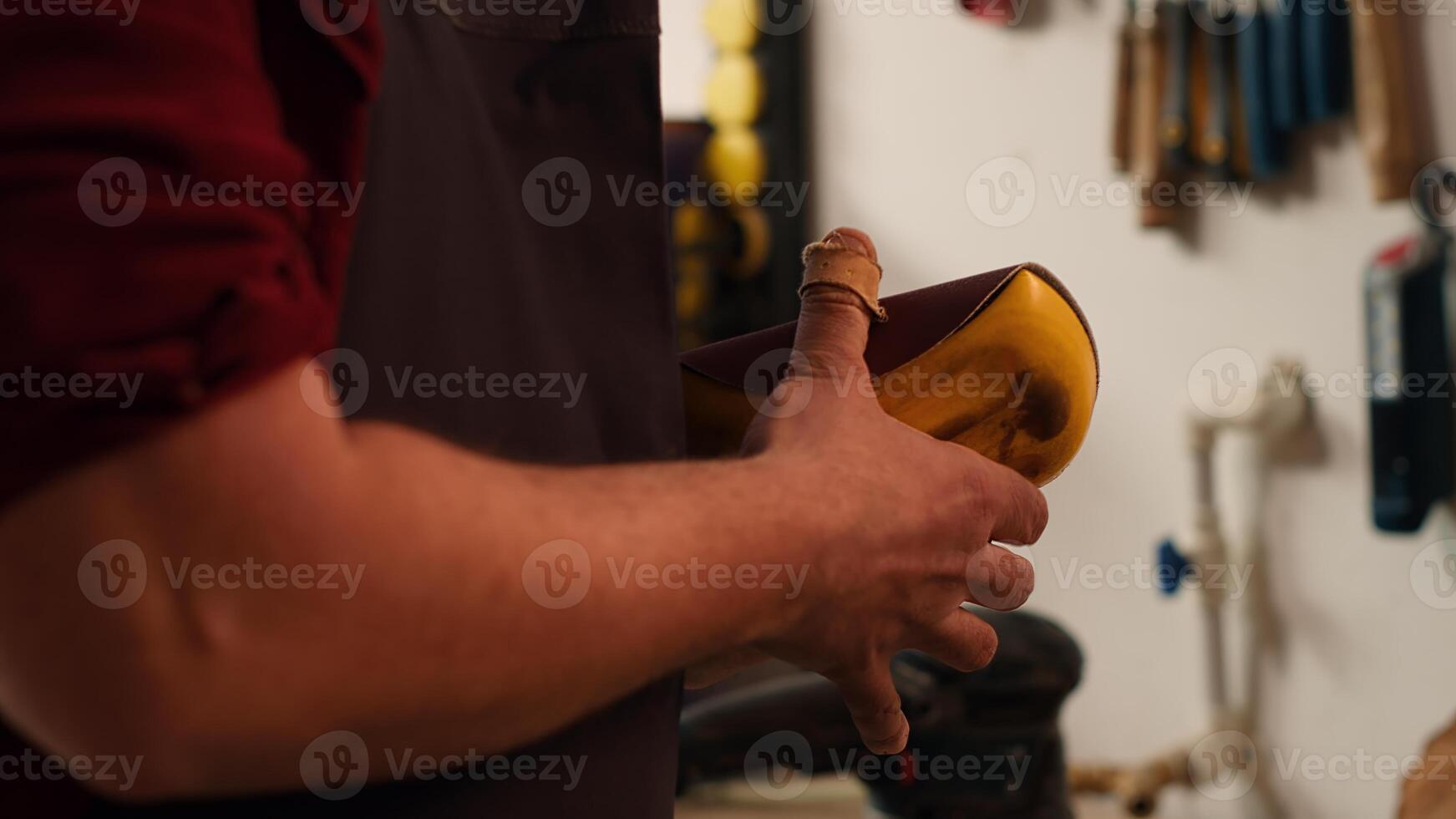 Carpenter putting sandpaper on piece of plastic, creating abrasive sponge to smooth surfaces. Man preparing necessary gear for furniture assembling job in studio, close up shot, camera A photo