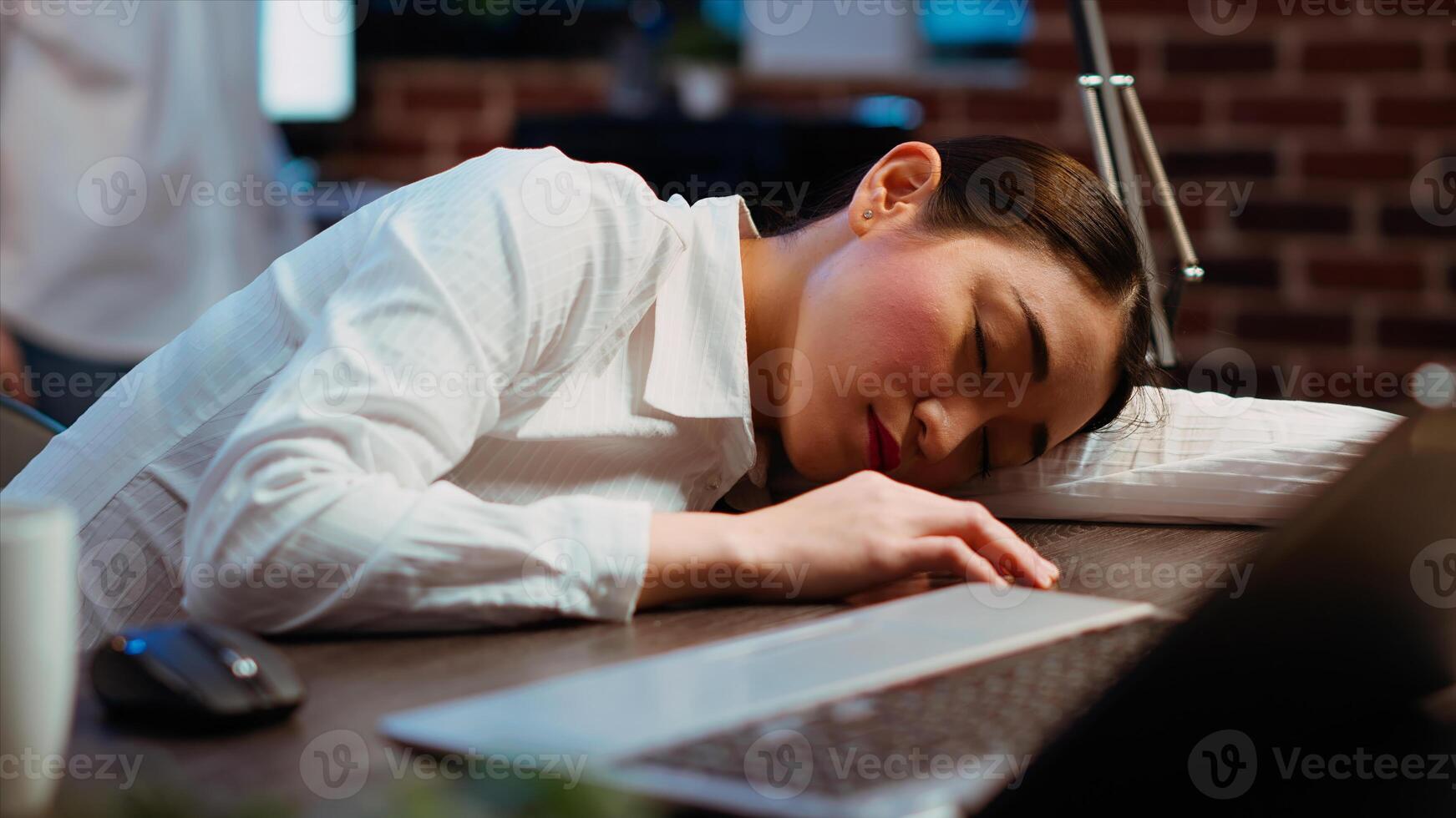 Tired employee sleeping on workspace desk, awaken by coworker, laughing about it. Close up shot of drowsy businesswoman woke up by colleague after napping in office working overnight photo