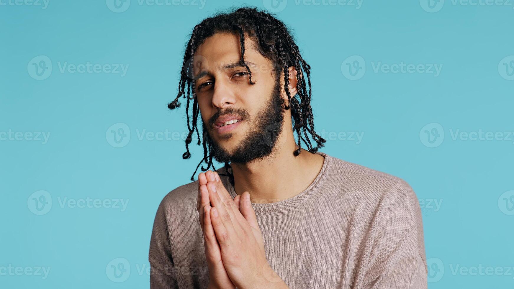 Desperate guy asking for forgiveness, putting hands together in imploring gesturing, showing regret emotion. Upset man saying sorry, begging for apology, feeling guilty, studio background, camera B photo