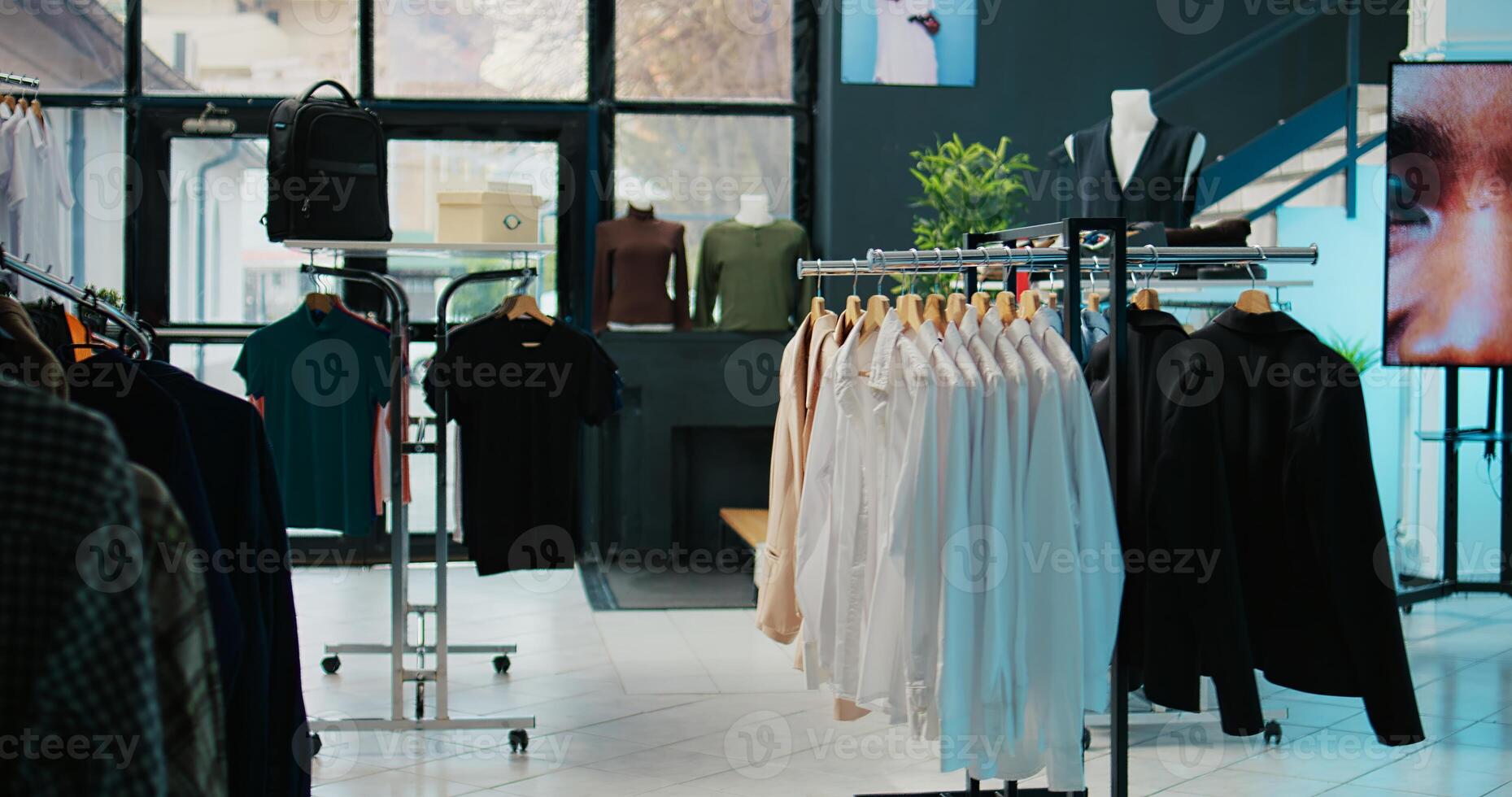 Tailoring boutique filled with new designer clothing line, racks hangers with trendy merchandise and cool accessories or shoes. Empty clothing store with stylish outerwear, small business. Camera B. photo
