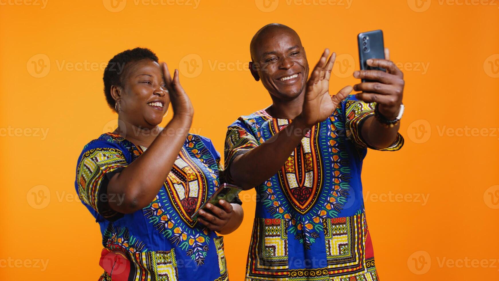 Ethnic couple waving hello on online videocall connection, using internet network and link to chat with family members. Husband and wife holding smartphone to talk to people on web. photo
