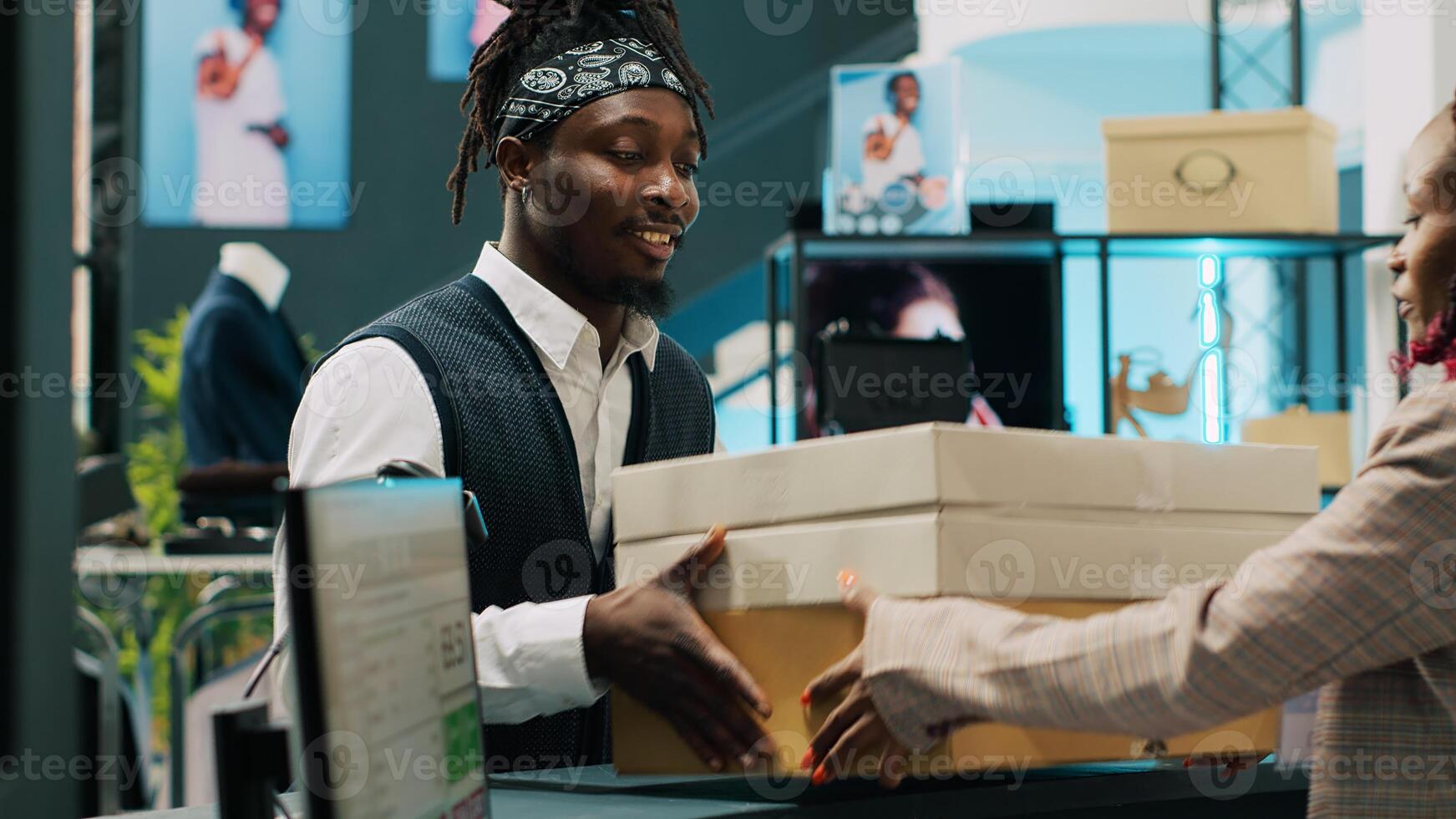 Retail employee picking up clothes order boxes from department store, signing invoice and confirmation papers at cash register counter. African american woman giving requested merchandise. Camera A. photo