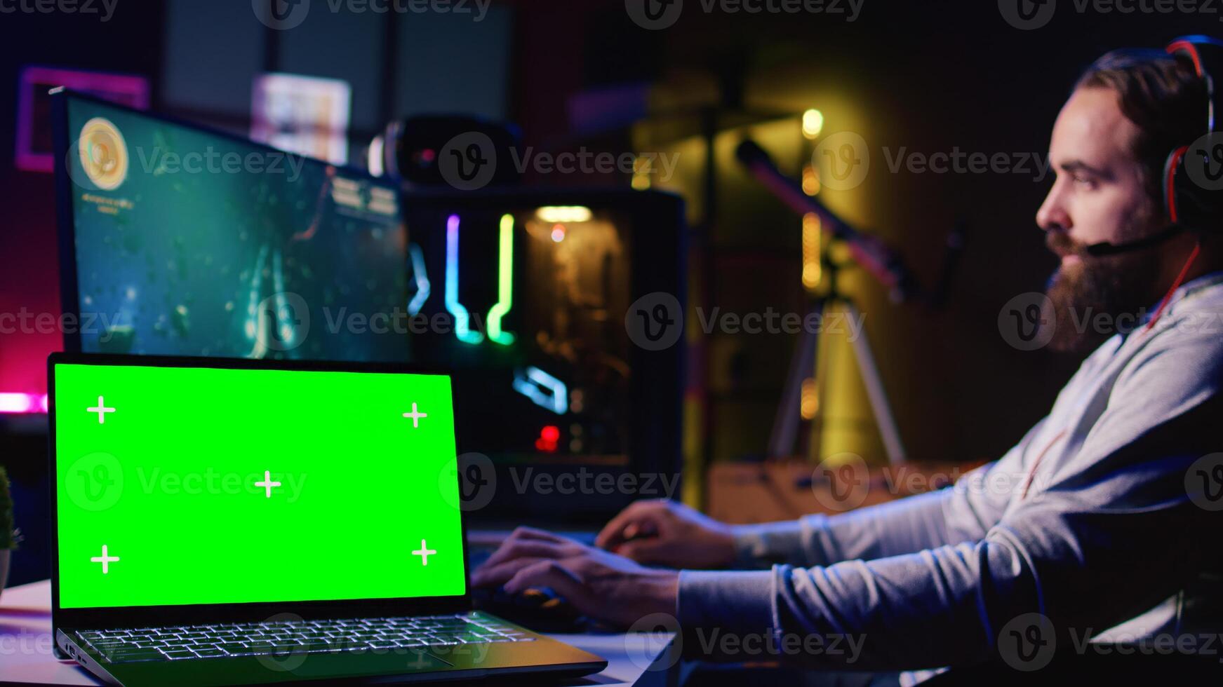 Zoom in on isolated screen laptop next to man using gaming keyboard to play flying singleplayer game. Chroma key notebook and gamer navigating with spacecraft in galaxy, shooting at asteroids photo