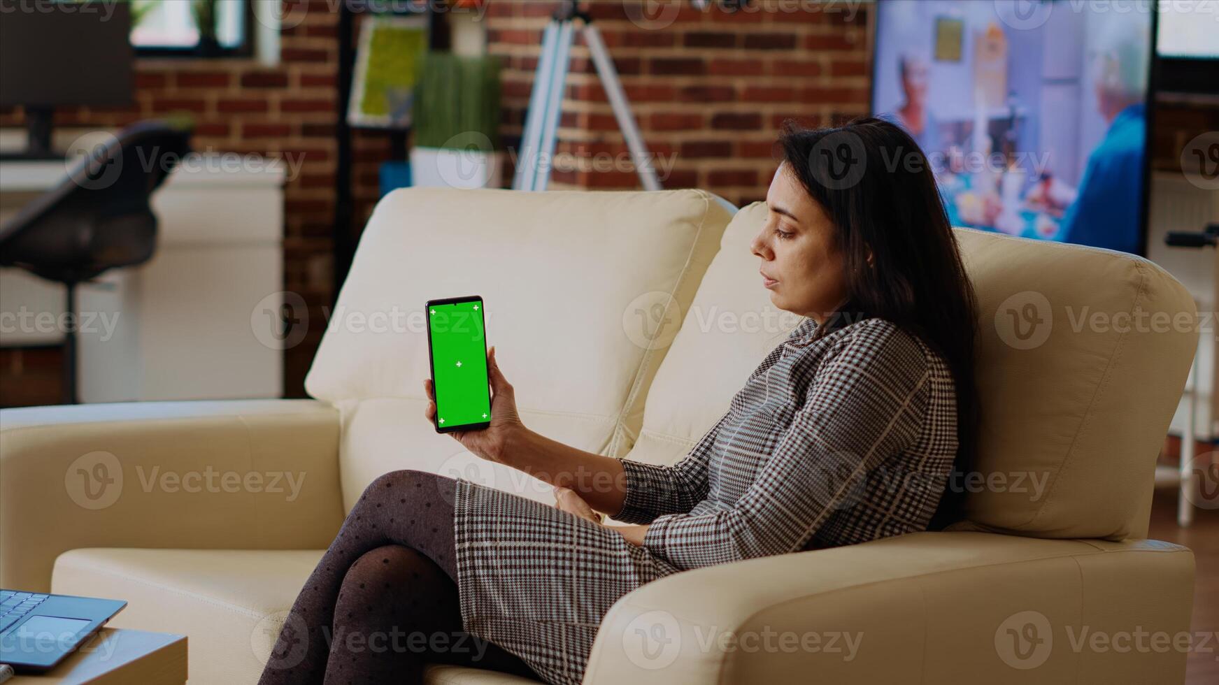 Person checking emails on green screen mobile phone during work from home. Indian woman in cozy apartment doing job tasks, reading business messages on mockup cellphone, panning shot photo
