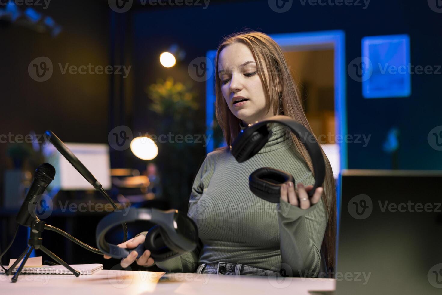 Internet show host holding pair of expensive headphones in hands, doing giveaway for loyal viewers from home studio. Content creator hosting online contest for fans with audio tech as prize photo