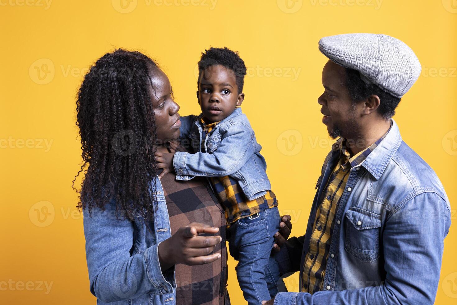 Portrait of african american family with a little child posing on camera, showing gratitude and sympathy towards each other and feeling satisfied. Happy mom and dad holding their boy. photo