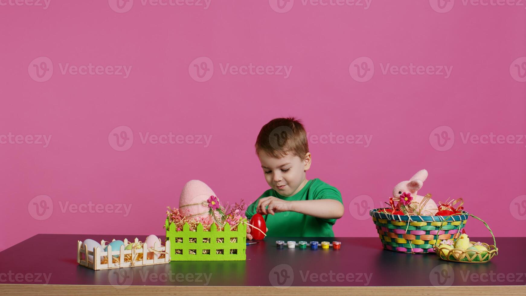 Ecstatic little kid using watercolor and paintbrushes to decorate eggs and create festive baskets as festive arrangements. Happy child enjoys painting and coloring decorations for easter. Camera B. photo