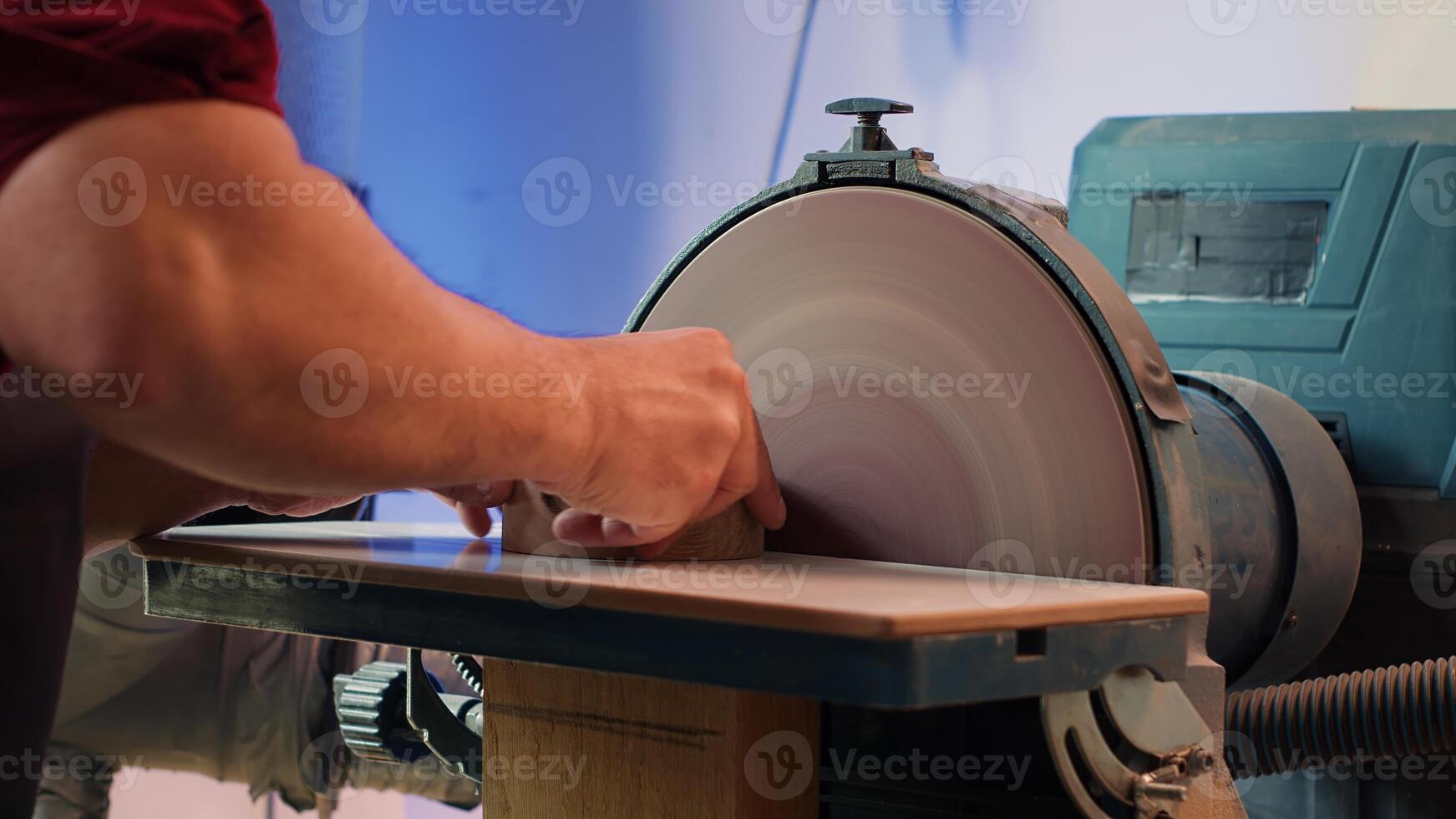 Woodworker shaping wooden bowl on disc sander in carpentry shop, showcasing precision. Cabinetmaker working in joinery, guiding wood against grinding machine rotating disc, camera A close up photo