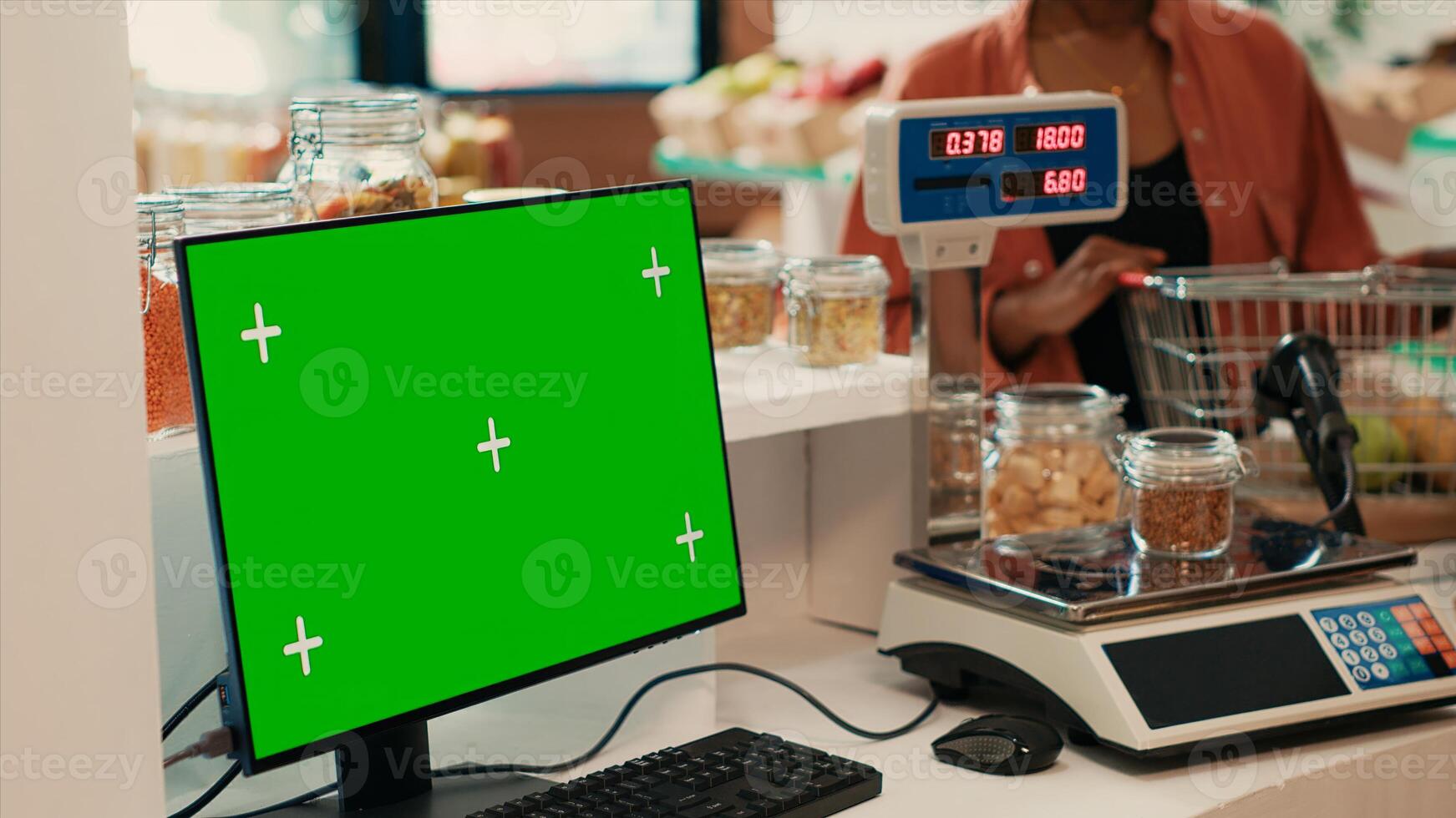 Merchant selling goods next to pc with greenscreen at checkout, locally grown fruits and veggies for sustainable lifestyle. Computer monitor running isolated chromakey display and mockup. photo