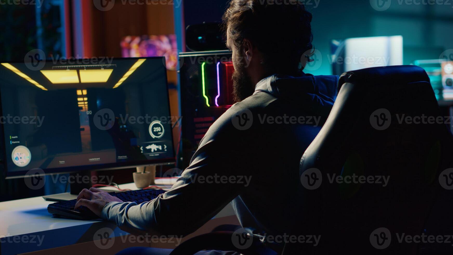 Man sitting on gaming chair, playing first person shooter videogame with gun shooting laser bullets. Gamer arriving home, ready to start game with dark atmospheric industrial setting photo