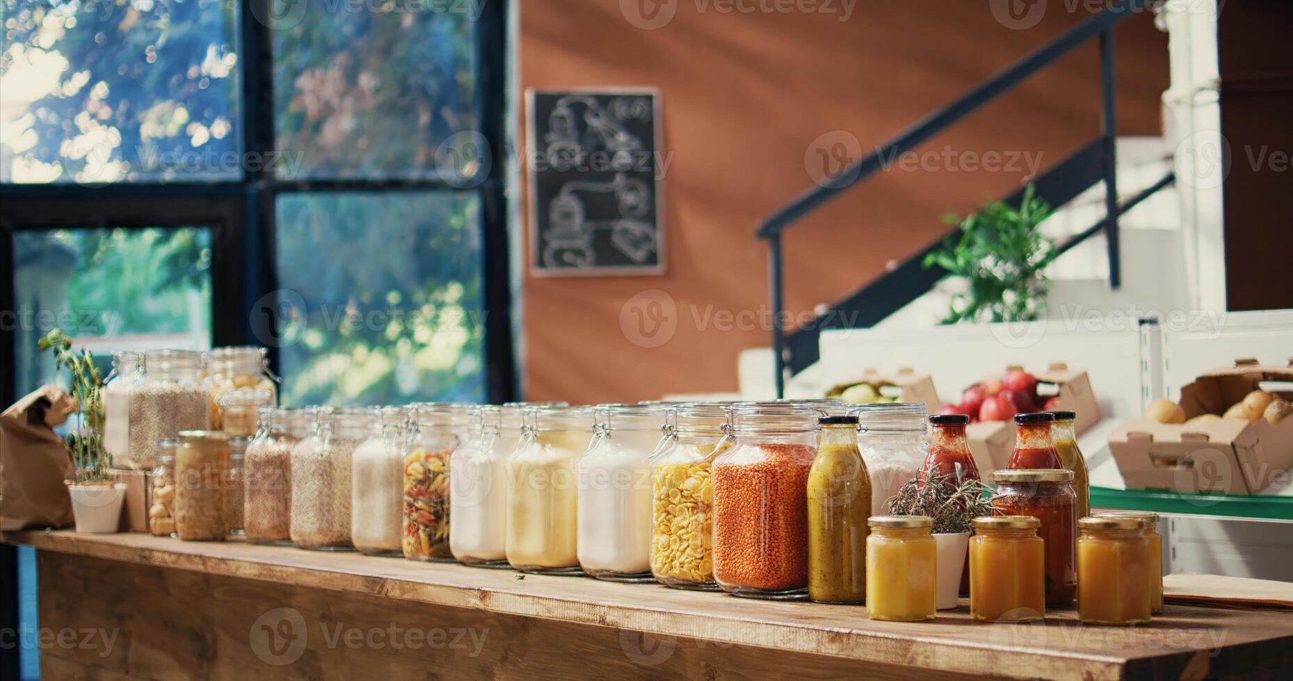 Pasta and sauces in reusable glass jars on store shelves, low carbon footprint sustainable lifestyle organic shop. Empty farmers market filled with bulk products and fresh produce. Handheld shot. photo