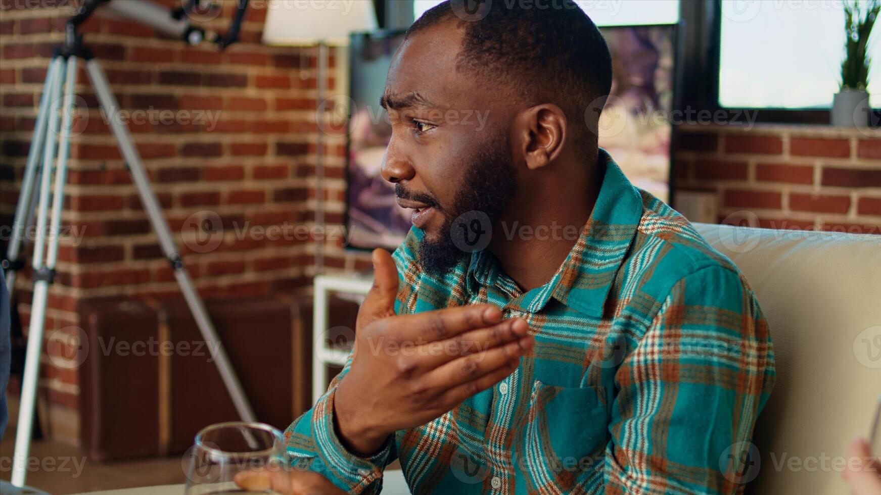Close up on african american man telling entertaining story to women at apartment party during weekend gathering. Group of friends listening to funny tale from host in living room, zoom in shot photo
