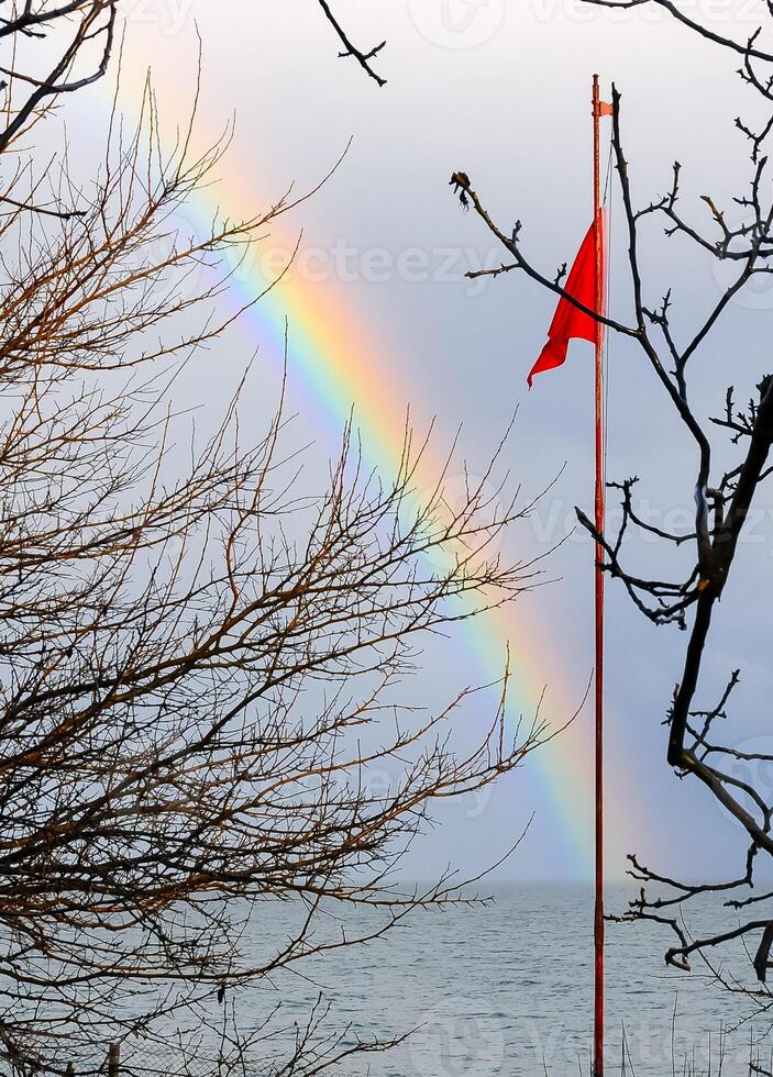Red flag on the background of a multi-colored rainbow over the sea, the Black Sea photo