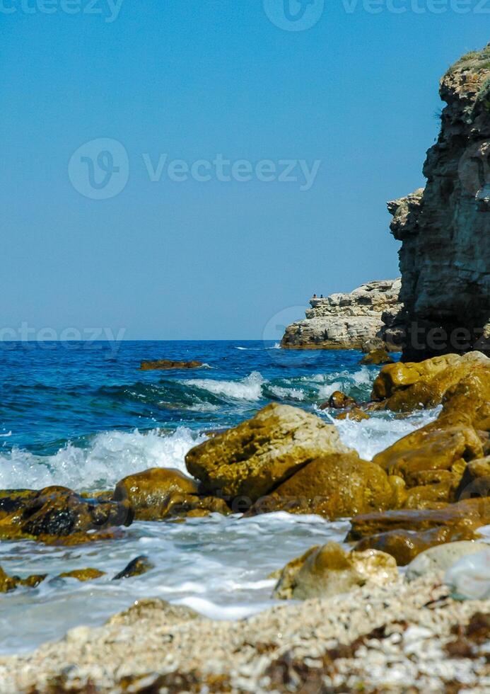 White waves on stones near the shore near the steep limestone shores and rocks in the tract Dzhangul, western Crimea photo