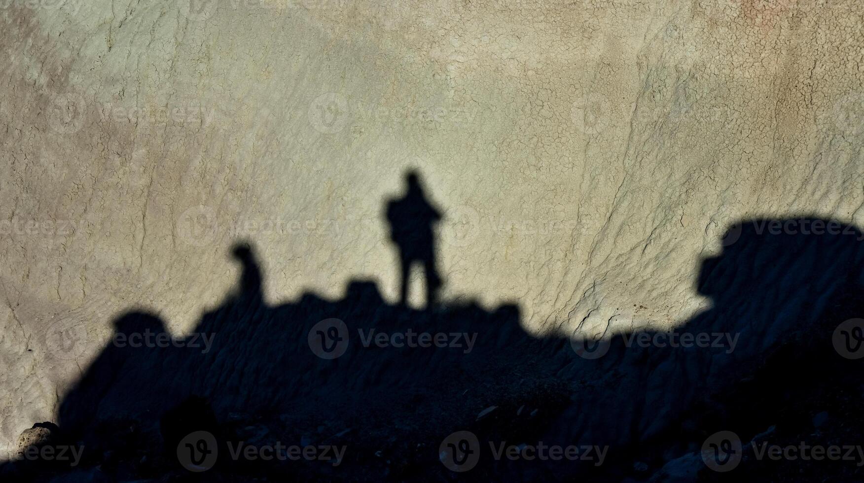Shadow of a man against a background of dry cracked clay, cracks on the ground. photo