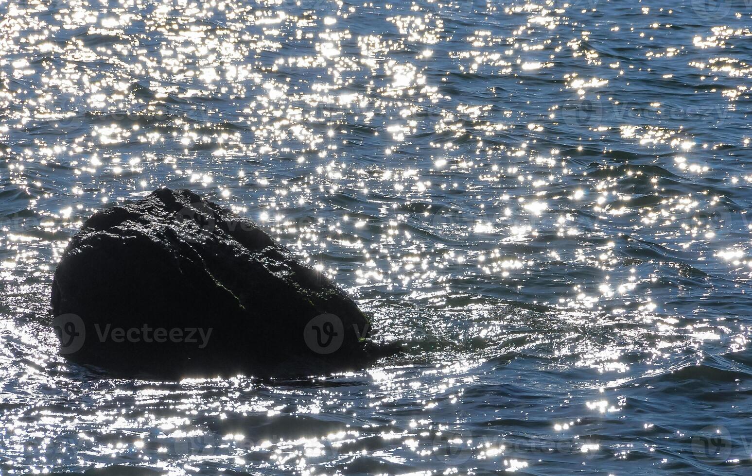 Bright reflections on the water on a sunny day among the coastal rocks near the Black Sea coast photo