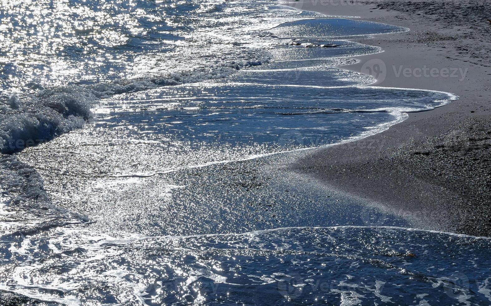Bright reflections on the water on a sunny day on the sandy shore of the Black Sea photo
