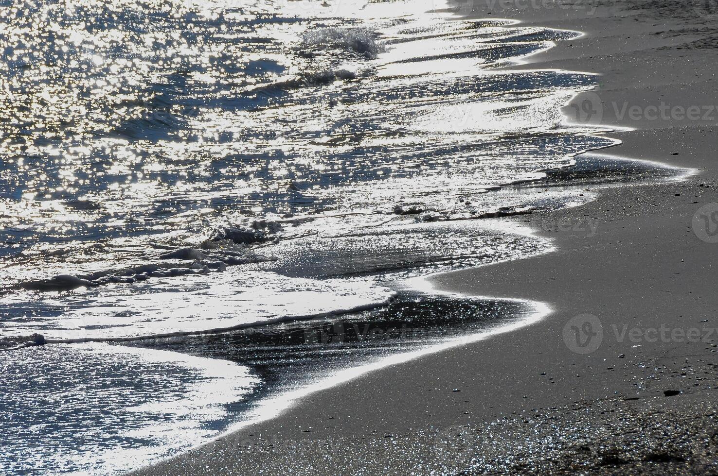 Bright reflections on the water on a sunny day on the sandy shore of the Black Sea photo