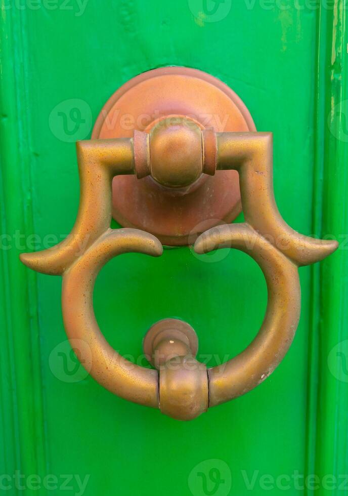 Traditional copper handle and door knocker on wooden doors of old houses in Malta, Gozo photo