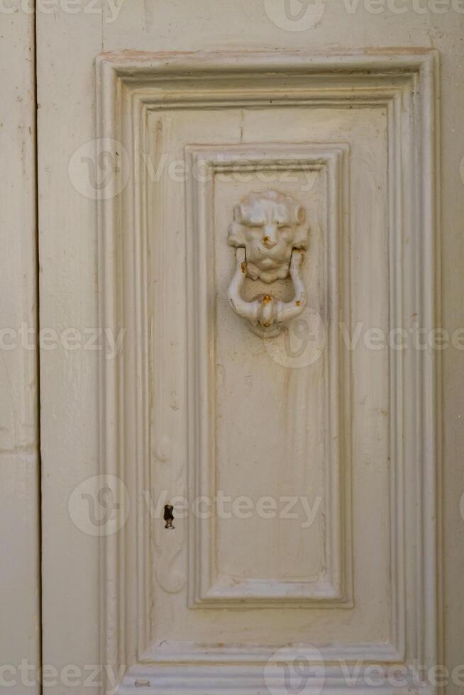 Traditional copper handle and door knocker on wooden doors of old houses in Malta photo