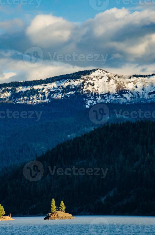 Mountains in the snow, overgrown with wood. Thick clouds over the mountains. photo