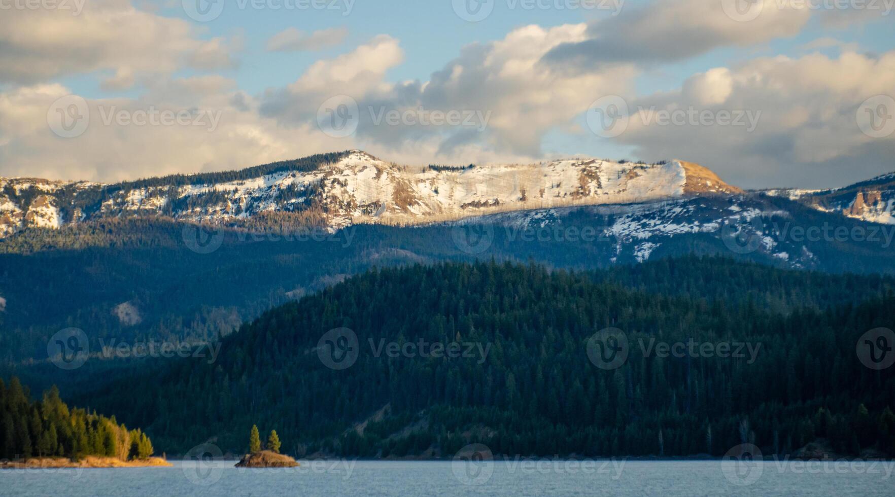 Mountains in the snow, overgrown with wood. Thick clouds over the mountains. photo