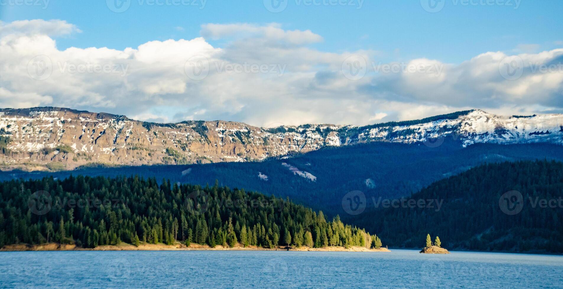 Mountains in the snow, overgrown with wood. Thick clouds over the mountains. photo